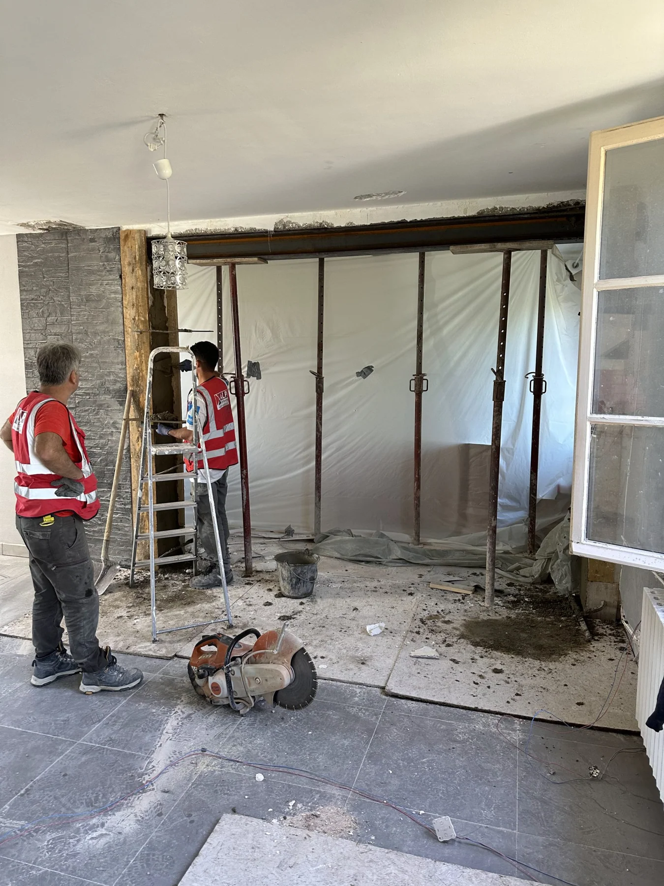 Deux salariés ALP interviennent autour d’une ouverture soutenue par des étais, dans un intérieur en rénovation.